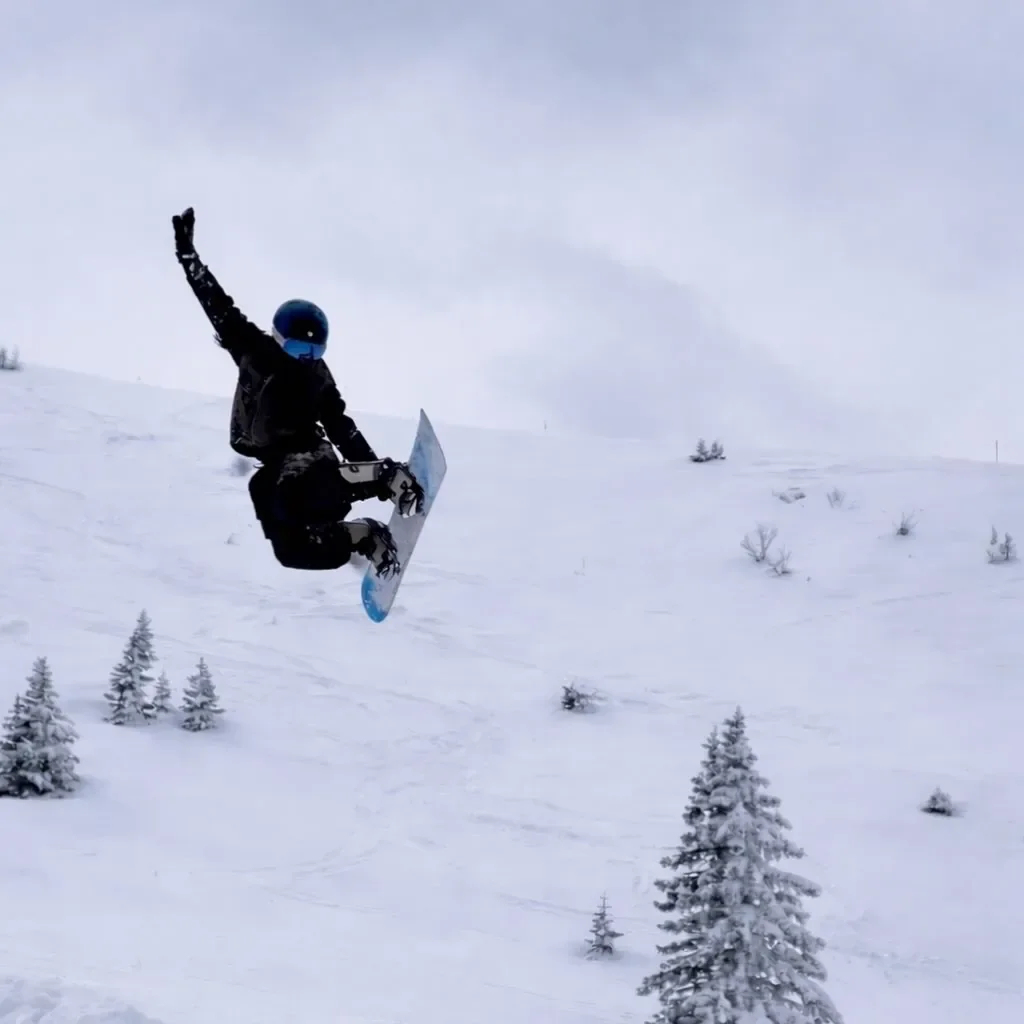 Snowboarder airborne above a snowy mountain slope